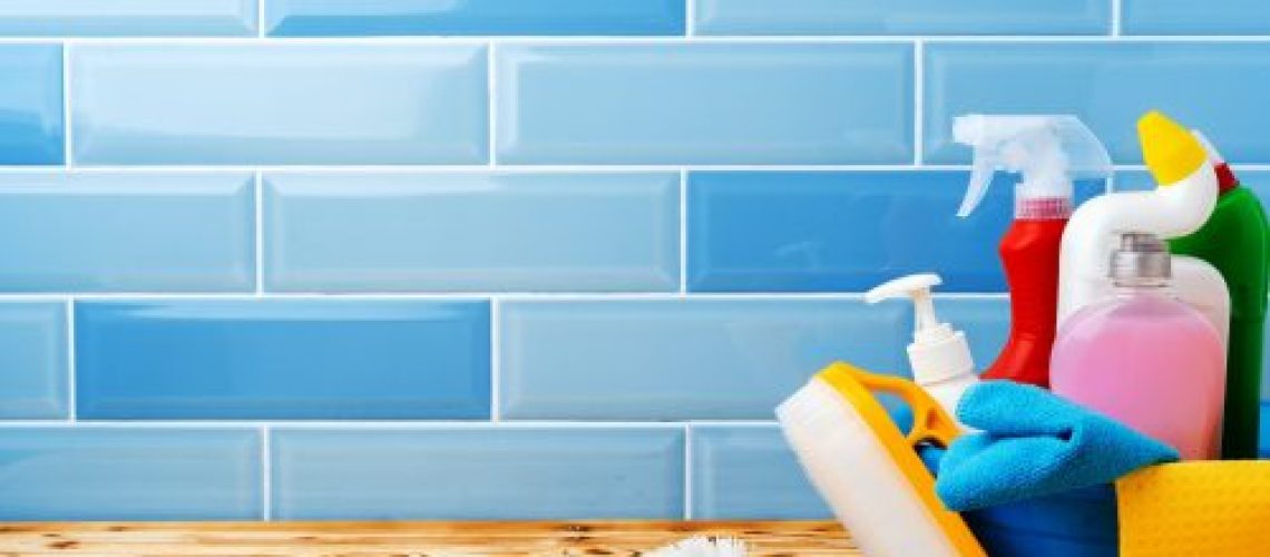 Household detergents and cleaning tools against blue tile background